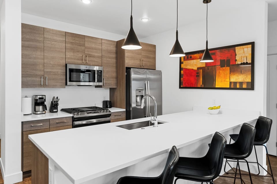 Your sleek kitchen features modern appliances and a spacious island where you can prepare meals or enjoy casual dining together.