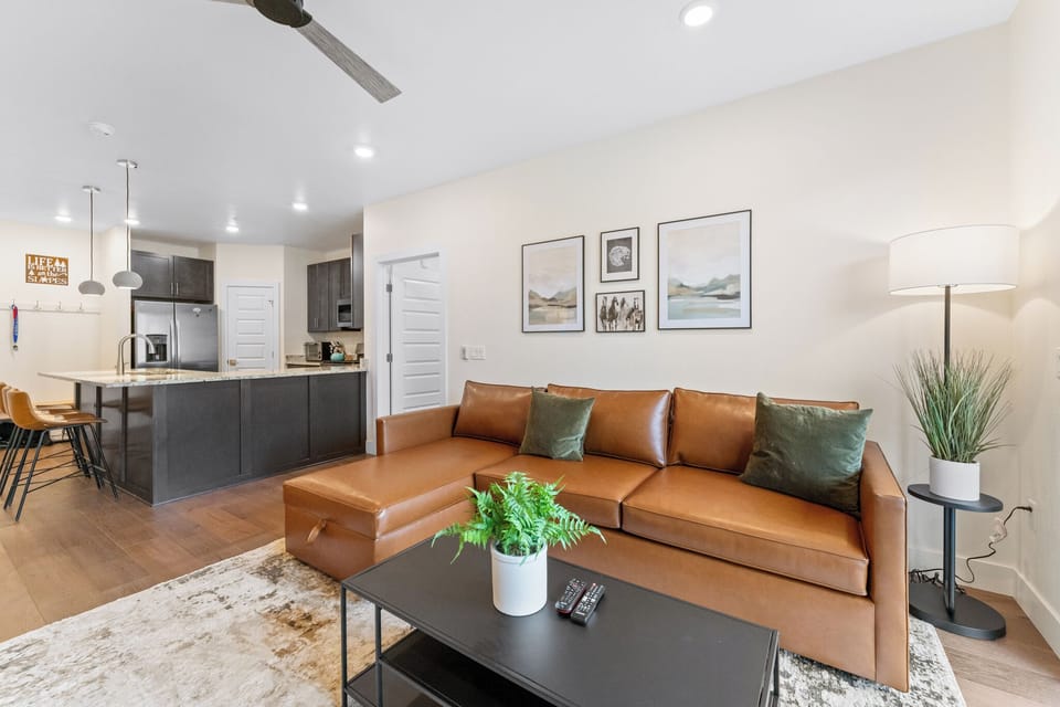 Sink into luxurious leather seating in your open-concept living space, where modern design meets comfort beneath soaring ceilings.