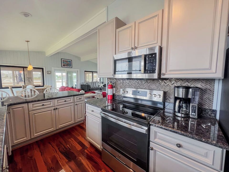 Your spacious kitchen awaits with gleaming countertops, modern appliances, and warm hardwood floors—ready for memorable meals and coastal mornings with coffee.