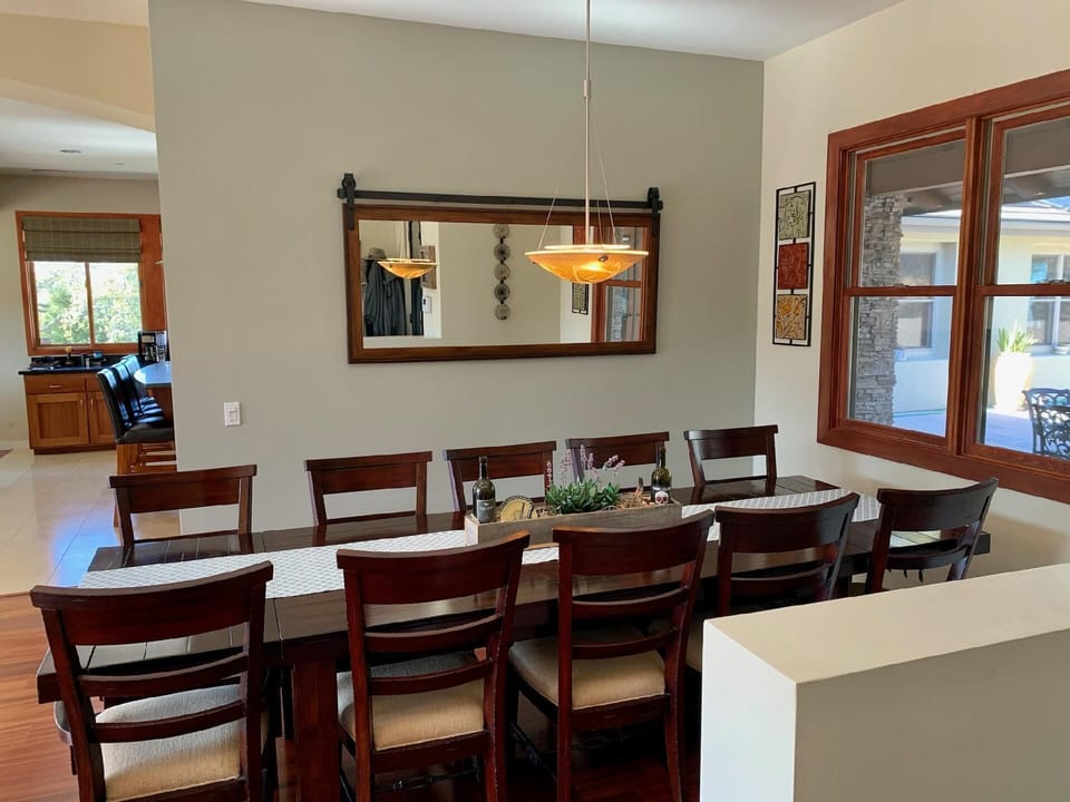 The formal dining area has an expansive dark wood table with seating for ten, anchored by an elegant pendant light.