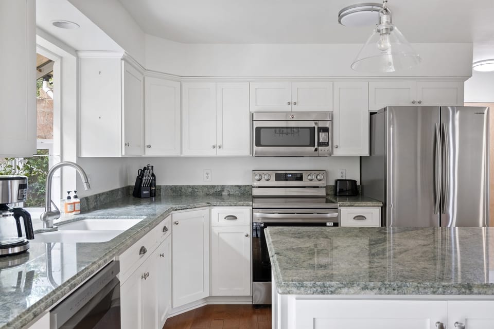 This chef-inspired kitchen shines with sleek stainless steel appliances, crisp white cabinetry, and stunning granite countertops.