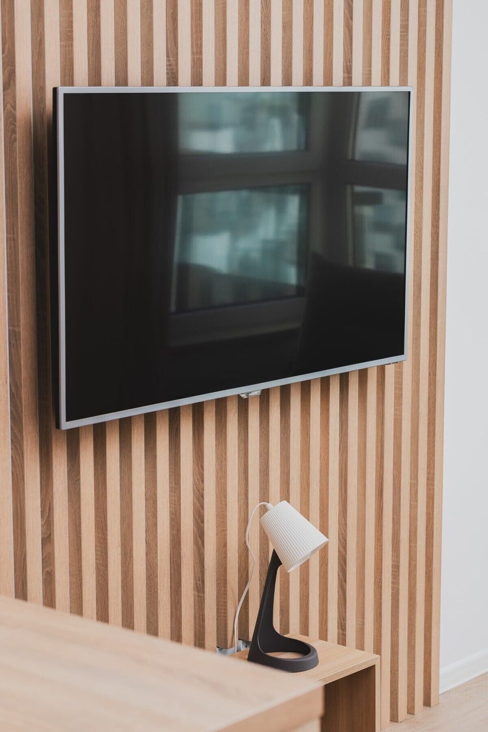  A modern wooden accent wall with a mounted TV, adding a warm, textured element to the space.