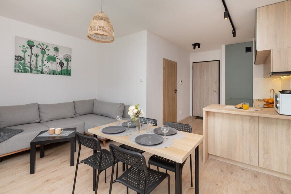 A view of the dining table set for four, adjacent to the kitchen, showing the open layout that connects the spaces seamlessly.