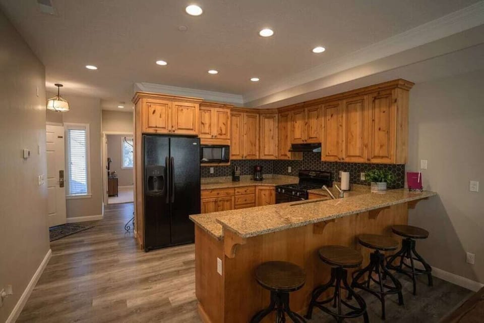 The gourmet kitchen features a breakfast bar with seating for four and is equipped with appliances, including a microwave, gas stove, and spacious refrigerator.