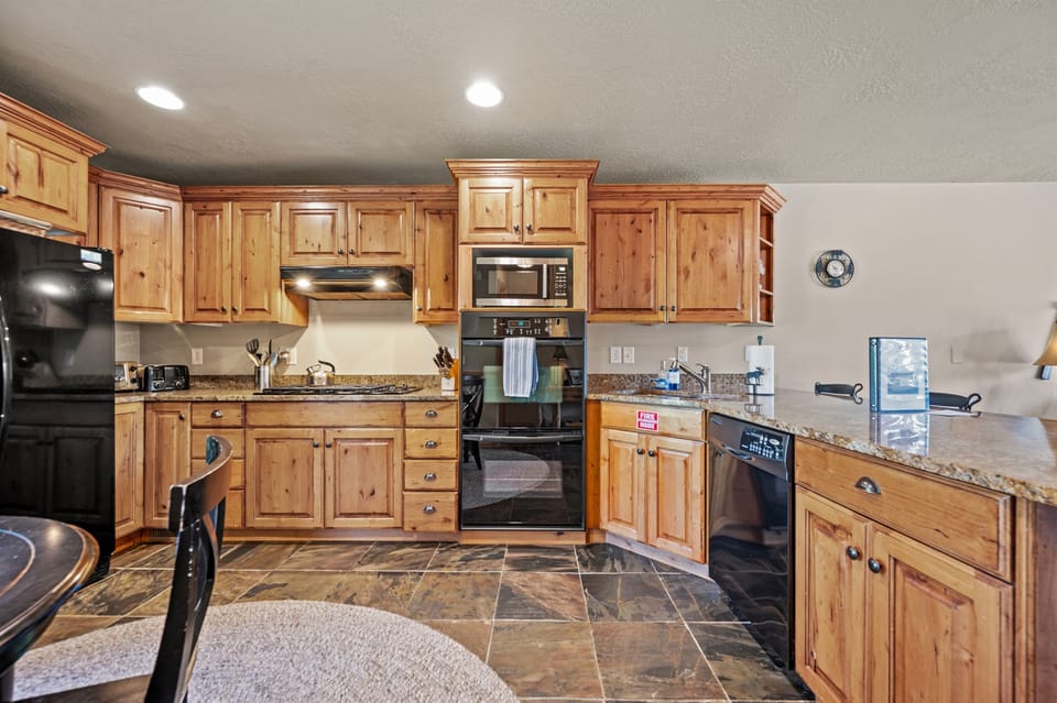 The gourmet kitchen features a breakfast bar with seating for four and is equipped with appliances, including a microwave, gas stove, and spacious refrigerator.