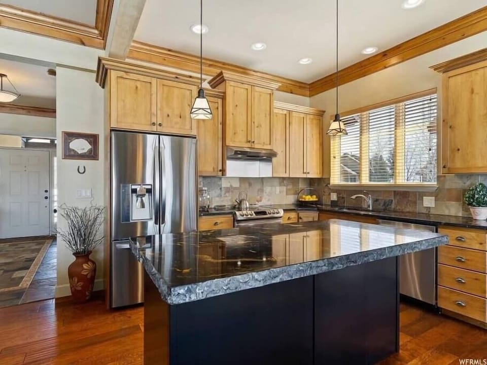 The gourmet kitchen features an island and is equipped with appliances, including a microwave, stove, and spacious refrigerator.