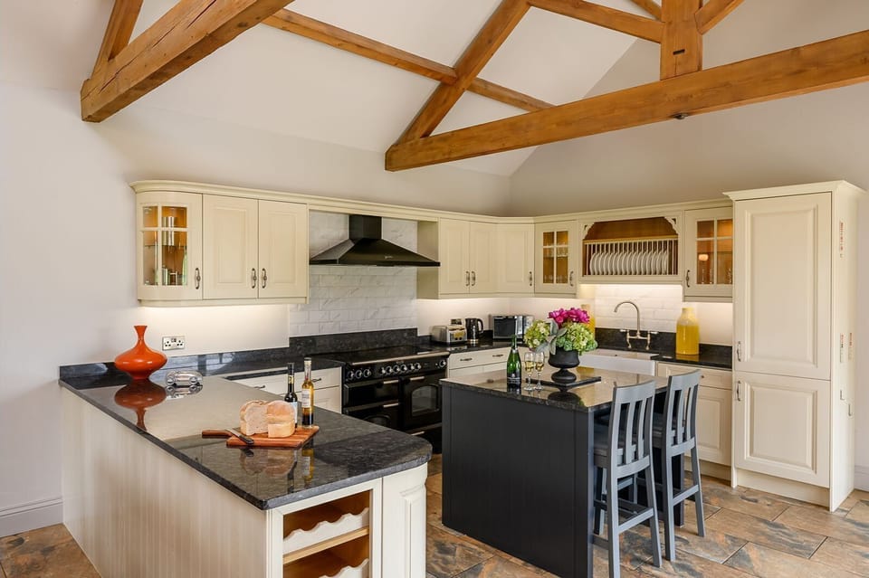 Open-plan living, dining and kitchen area at Kingfisher holiday cottage with exposed beams.