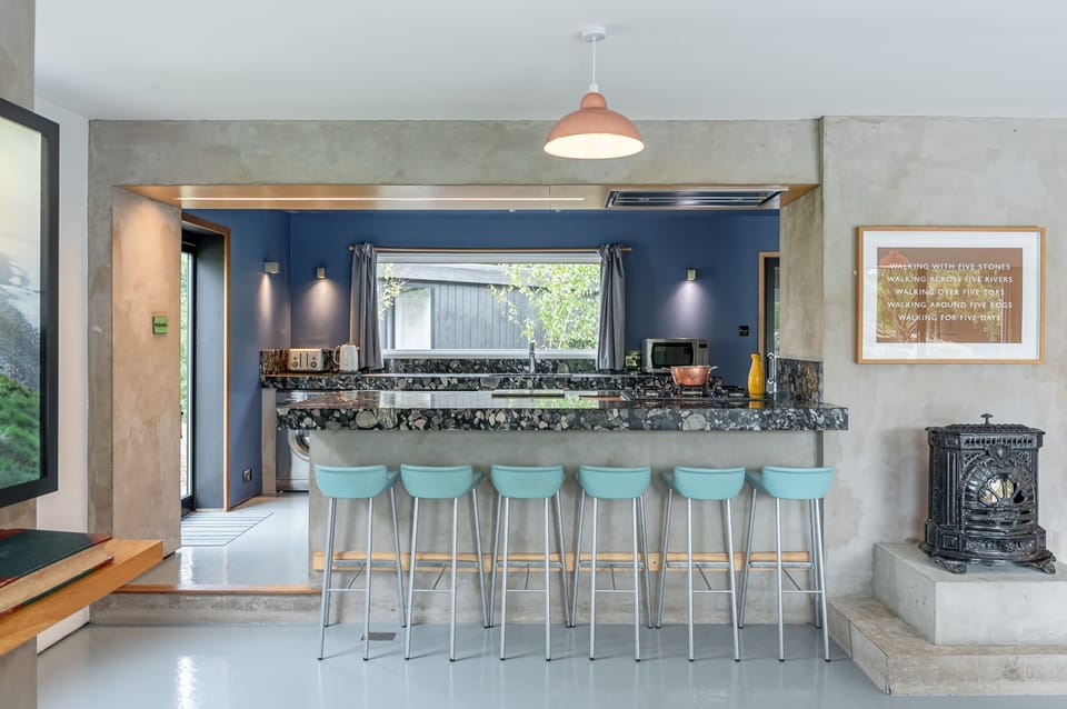 Modern kitchen with large breakfast bar, turquoise stools and open-plan countryside interior.