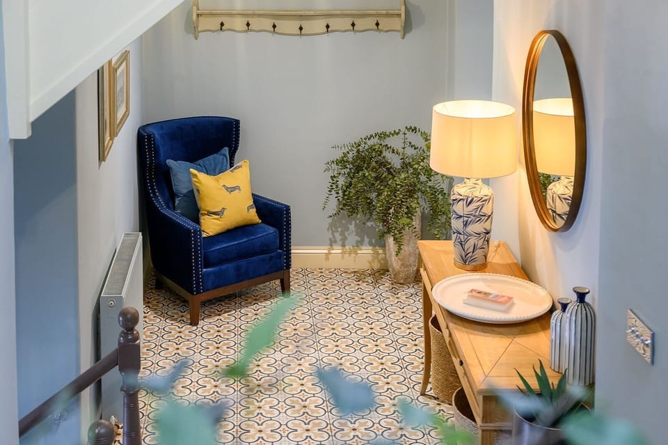 Hallway and staircase at 30 Frenchgate with patterned floor tiles, carpeted stairs, a hanging lantern light, and leaf artwork on the wall.