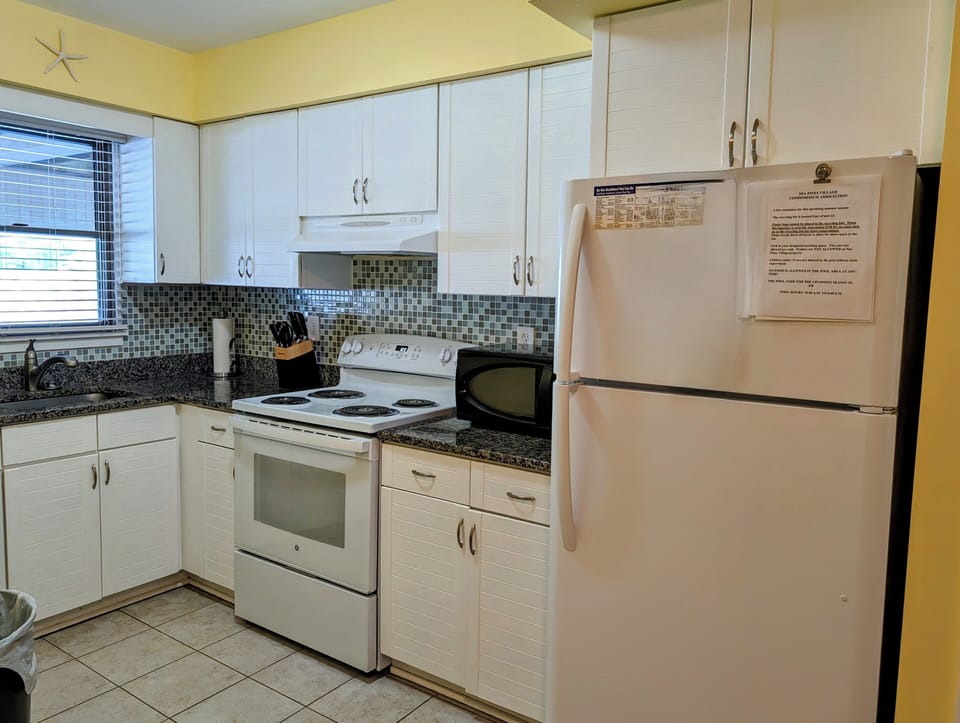 4 Lagoona Drive, Sea Pines, Bethany Beach-Kitchen & Appliances - View of the functional kitchen with white cabinets, dark granite countertops, and a full-size white refrigerator.