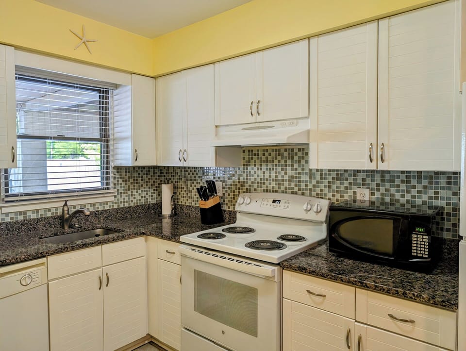 4 Lagoona Drive, Sea Pines, Bethany Beach -Kitchen Sink View - Perspective of the kitchen workspace featuring a mosaic tile backsplash and a view of the breakfast bar.