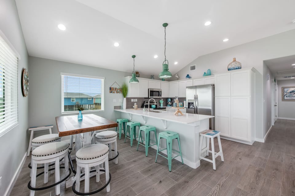 Your bright, coastal-inspired kitchen invites family gatherings with its spacious island, charming turquoise accents, and cozy dining nook perfect for morning coffee.
