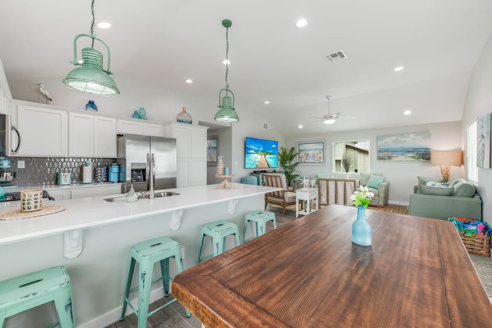 Your spacious open-concept living area features a fully-equipped kitchen, cozy dining space, and relaxing lounge with coastal-inspired mint green accents throughout.