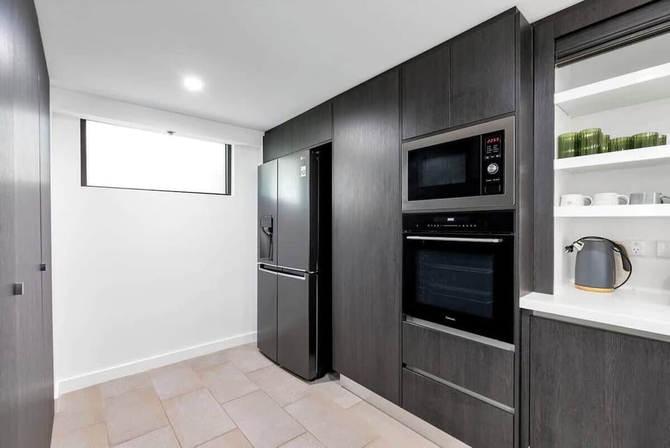 The kitchen has chic dark wooden cabinets with ample storage, so you can ensure you have everything needed to begin your cooking adventures. 
