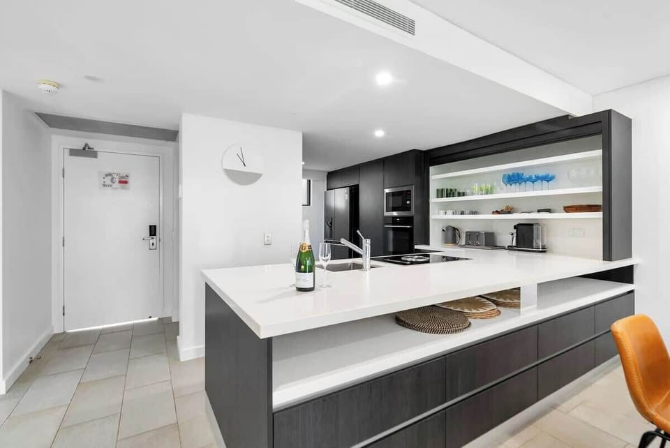 The contemporary kitchen has a spacious bench area with an induction stove, coffee, and appliance nook with retractable tidy doors and a large French door fridge. 
