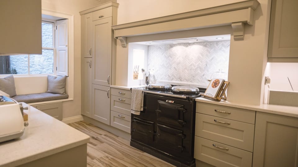Porte House kitchen with traditional range cooker, shaker-style units and window seat.