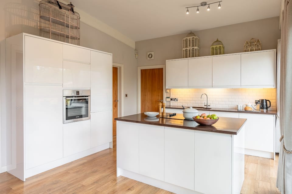 Kitchen at Abbey, featuring a central island with hob, built-in oven, integrated storage, and generous workspace.