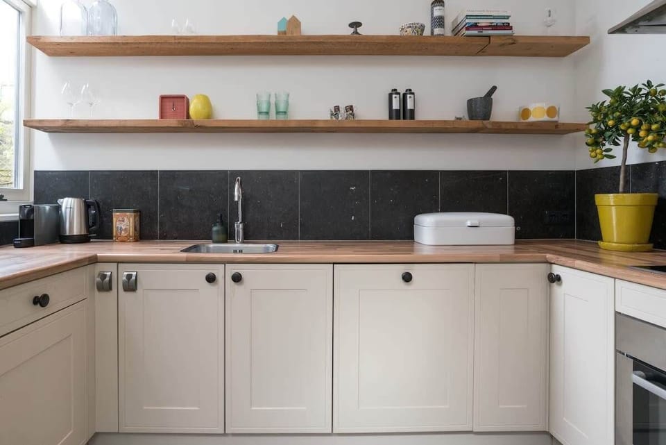 Fully equipped kitchen with natural wood shelves and modern appliances — cook, dine and feel right at home.


