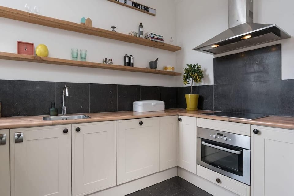 Fully equipped kitchen with natural wood shelves and modern appliances — cook, dine and feel right at home.

