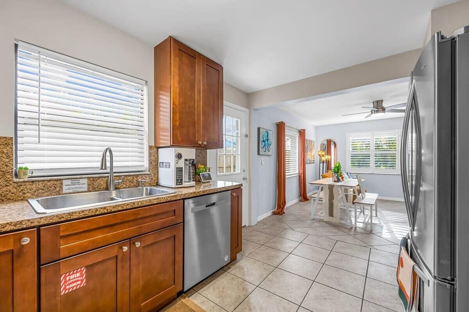 Bright kitchen with wooden cabinets and stainless steel appliances opening to a cozy dining area.