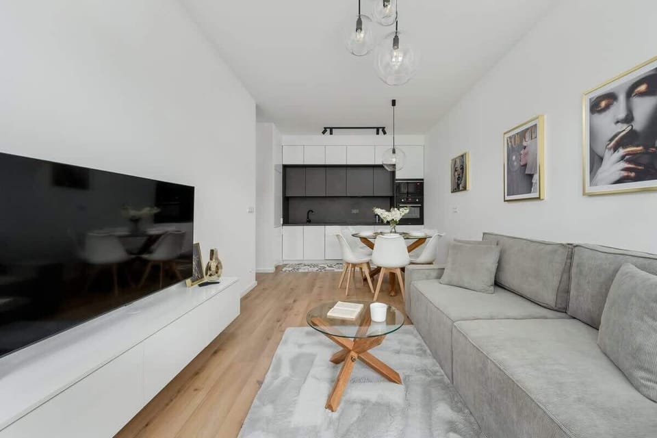 A living area with a soft grey sofa, TV, and a light wooden floor. Comfortable and inviting design.