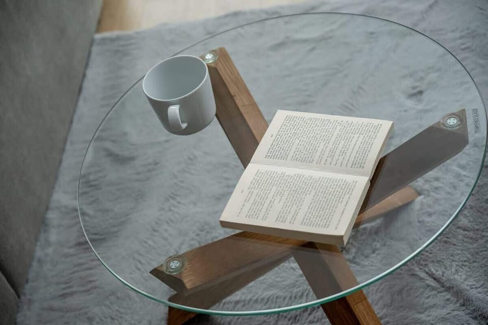 A close-up of a book and glasses on a round coffee table. A peaceful corner for reading.