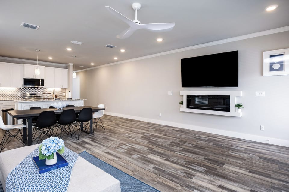 Relax in your stylish open-plan living space with modern fireplace, large TV, and sleek kitchen perfect for entertaining.