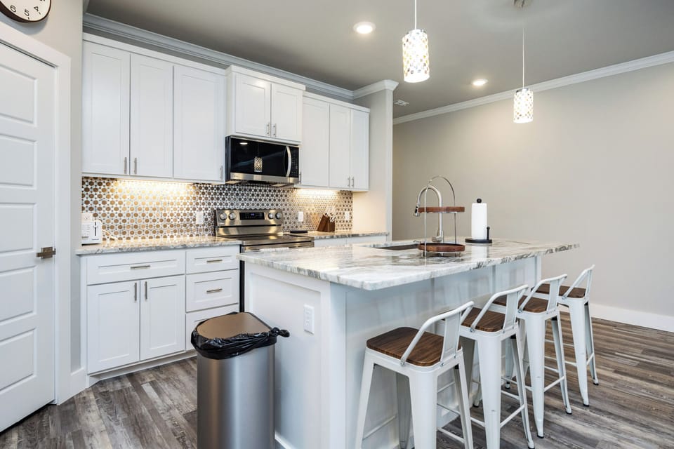 Your sleek kitchen awaits with marble counters, gleaming appliances, and a breakfast bar perfect for morning coffee or evening conversations.