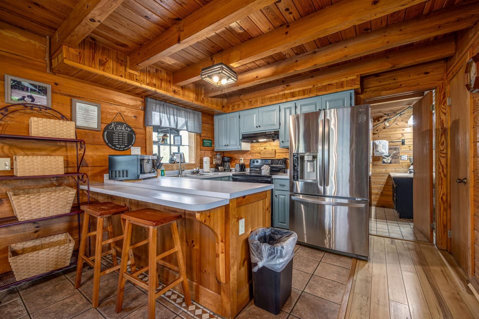 Your rustic cabin kitchen features modern stainless steel appliances and a cozy breakfast bar perfect for morning coffee.