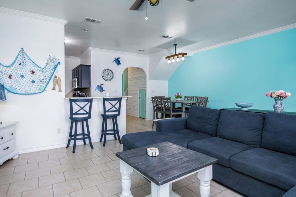 Relax in your coastal-themed living space where nautical décor meets comfort—sink into the plush navy sofa while ocean breezes flow through.