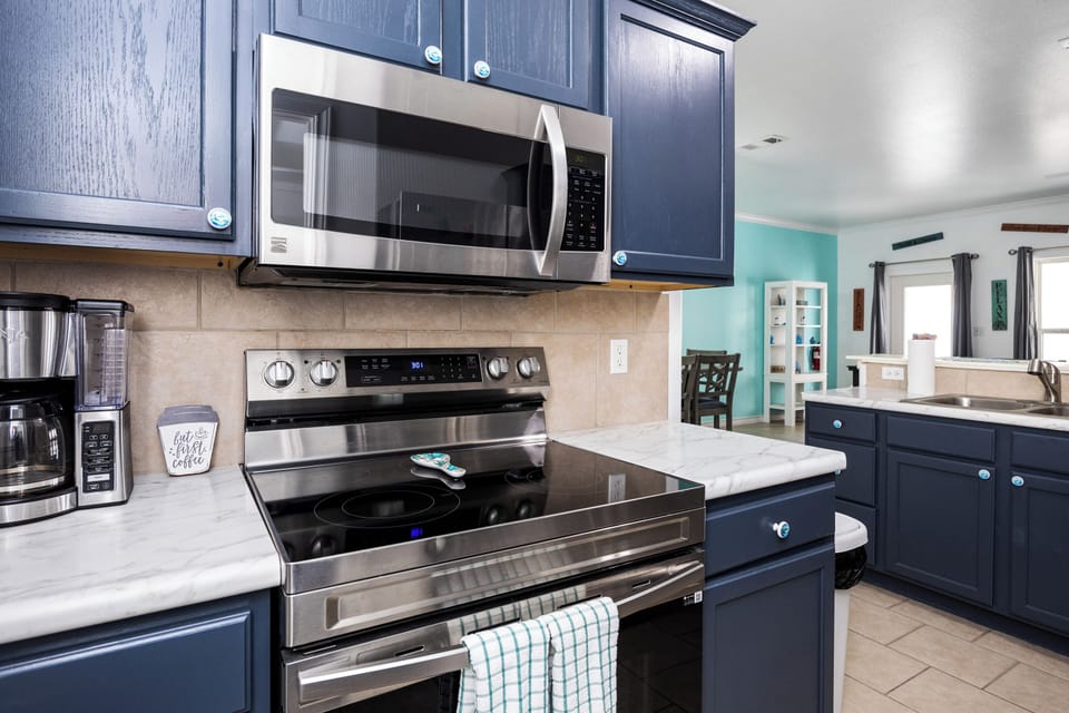 Your fully-equipped kitchen awaits with modern appliances and sleek navy cabinets, perfect for preparing memorable meals during your stay.
