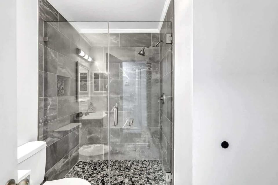 Modern bathroom featuring a glass-enclosed shower with stone tile flooring.