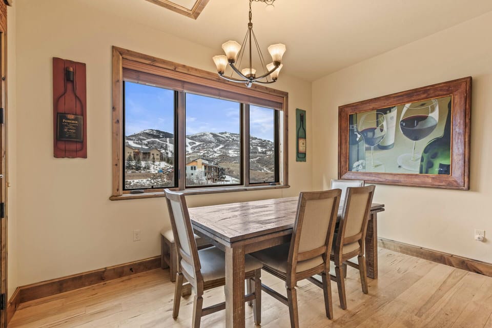 Gather around this inviting dining table with stunning mountain views framing your meals. Natural light streams through the skylight, illuminating warm wood accents and creating a perfect space for memorable dinners with loved ones.