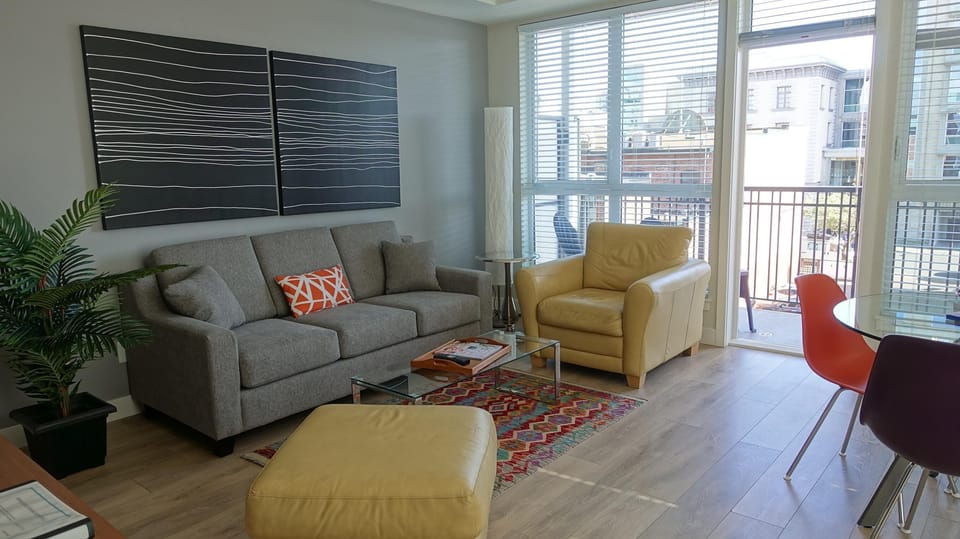Secondary living room view showing floor-to-ceiling exterior windows and adjacent dining space.