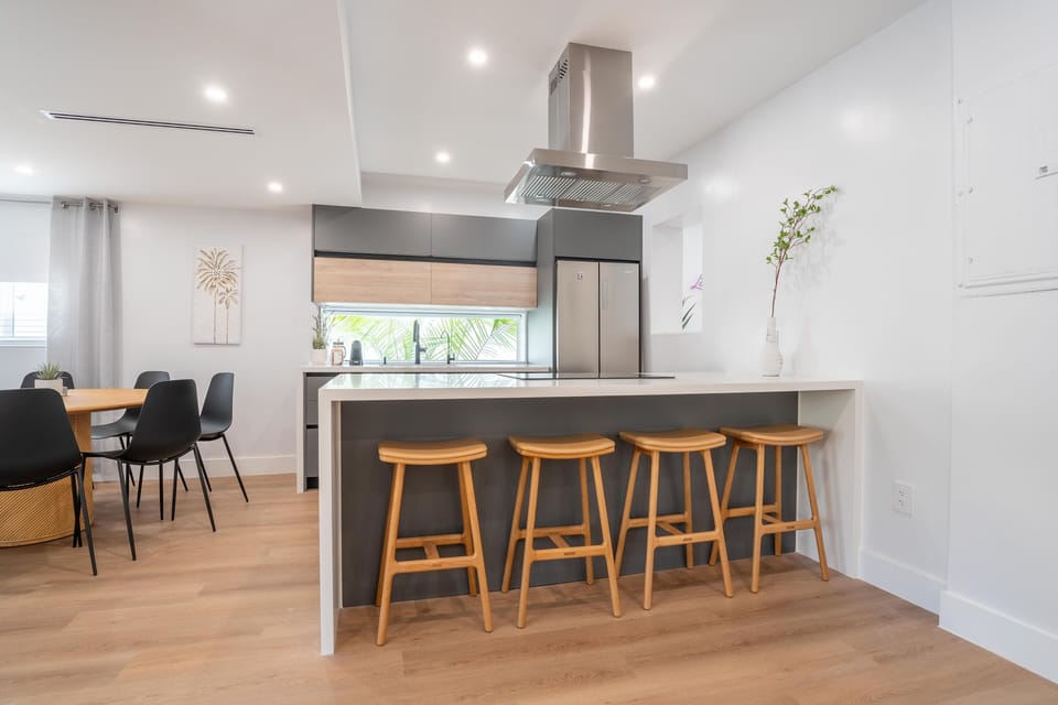 Kitchen features a waterfall quartz countertop island & four leather stools.