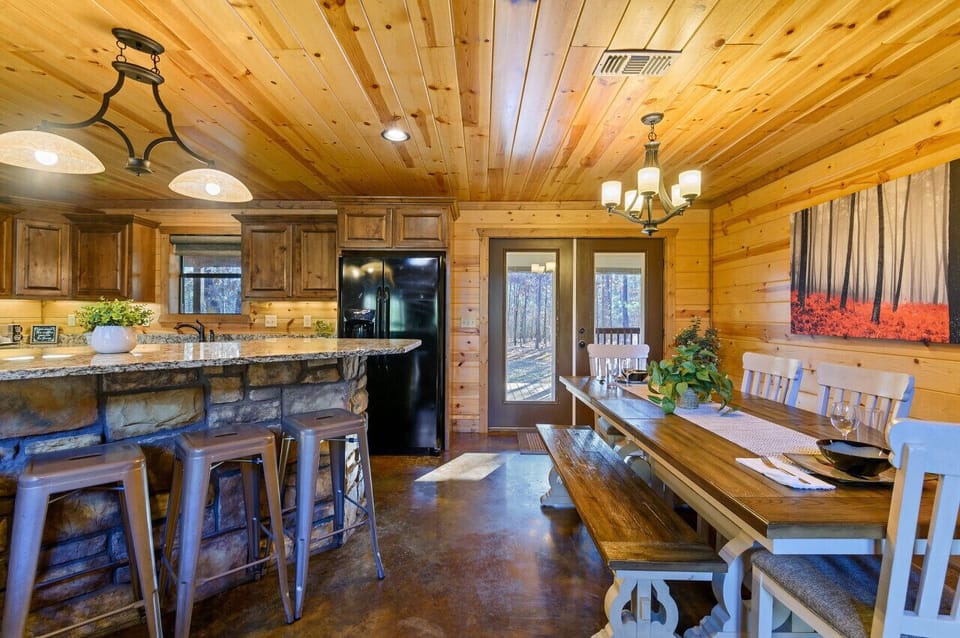 Fully stocked kitchen with granite counters, stainless appliances, large island, and seating that flows into the dining area.