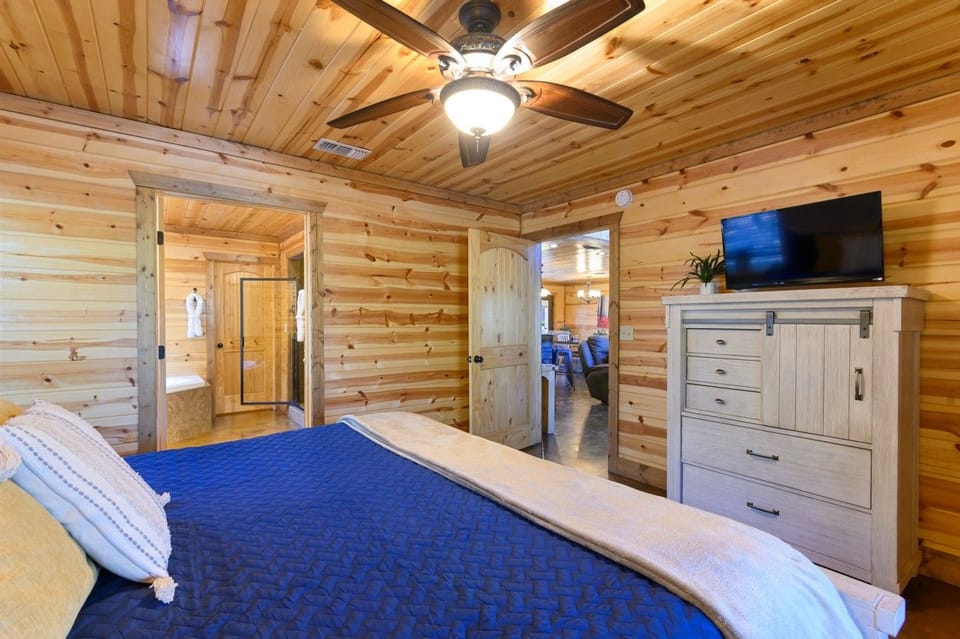 King bedroom with navy bedding, dresser and wall-mounted TV.