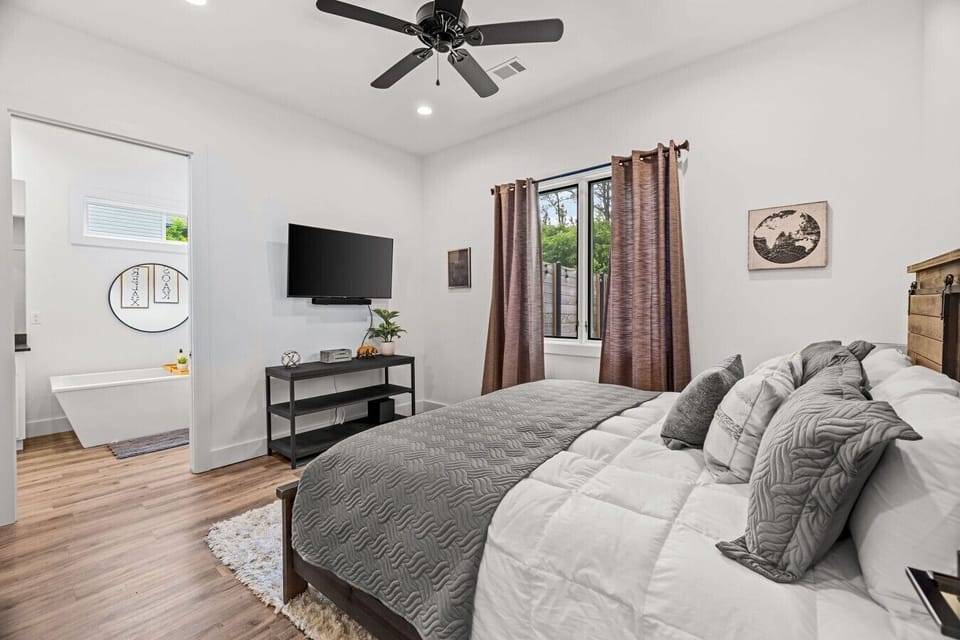 Bedroom with wall-mounted TV, media stand and layered bedding.