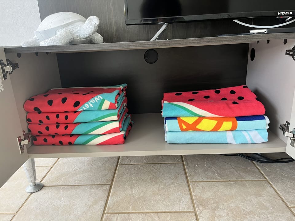 Beach and pool towels are located in the living room in the TV cabinet.