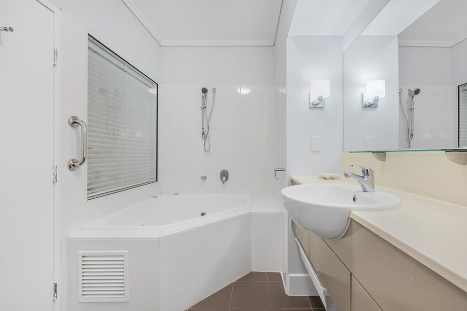 Modern bathroom with a large mirror, sinks, and a shower