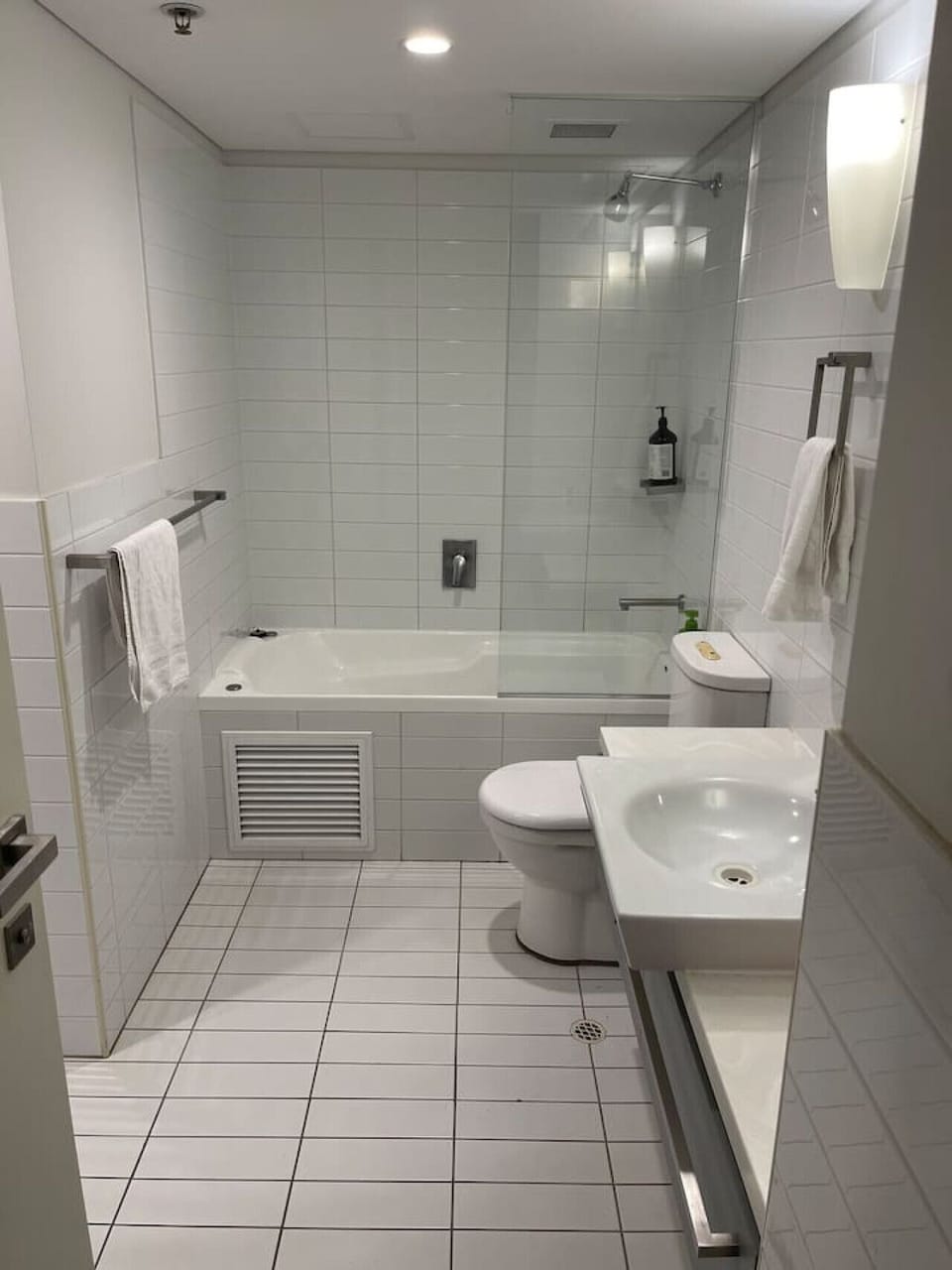 Clean white tub, toilet, and towel rack with ample light.