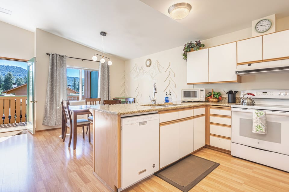Open floor plan living, dining, kitchen with door out to private deck and views