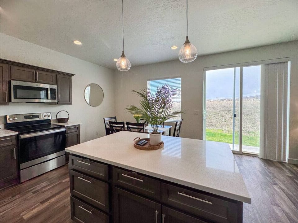 Bright and modern kitchen with island seating and scenic backyard views—perfect for cooking, dining, and making memories together.