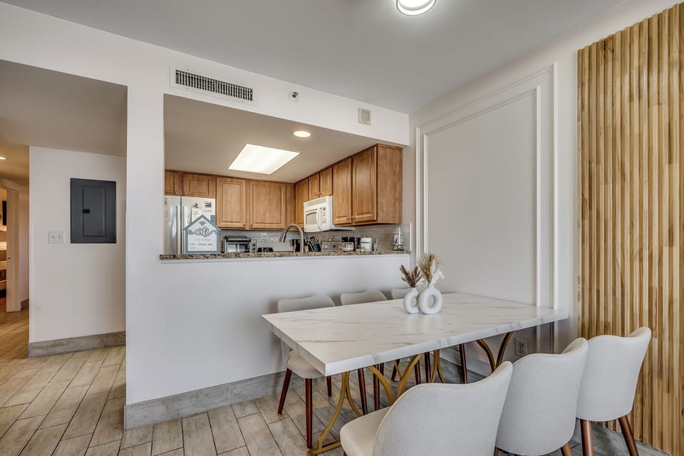 A bright dining area with a view into the kitche.
