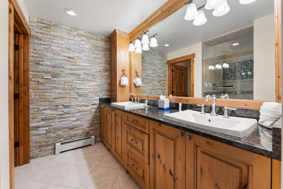 Unwind in your spa-like bathroom featuring rustic stone walls, elegant granite counters, and premium fixtures for ultimate relaxation.