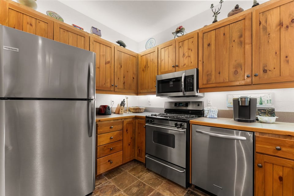 Your fully equipped kitchen features warm wood cabinets and stainless steel appliances, perfect for preparing meals together during your stay.