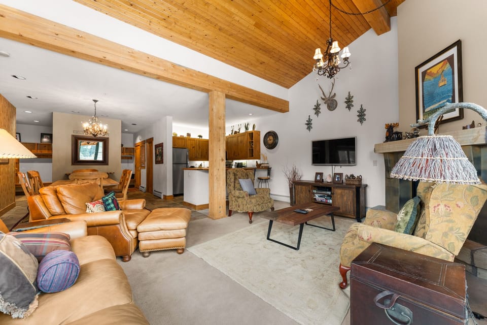 Sink into plush leather seating beneath soaring wood beams, where your crackling fireplace creates the perfect mountain retreat atmosphere.
