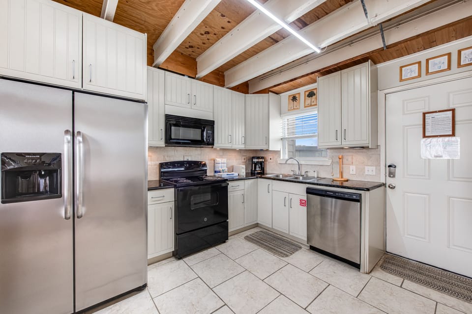 Your fully equipped kitchen features stainless steel appliances and charming exposed wood beams overhead, perfect for cooking memorable meals together.