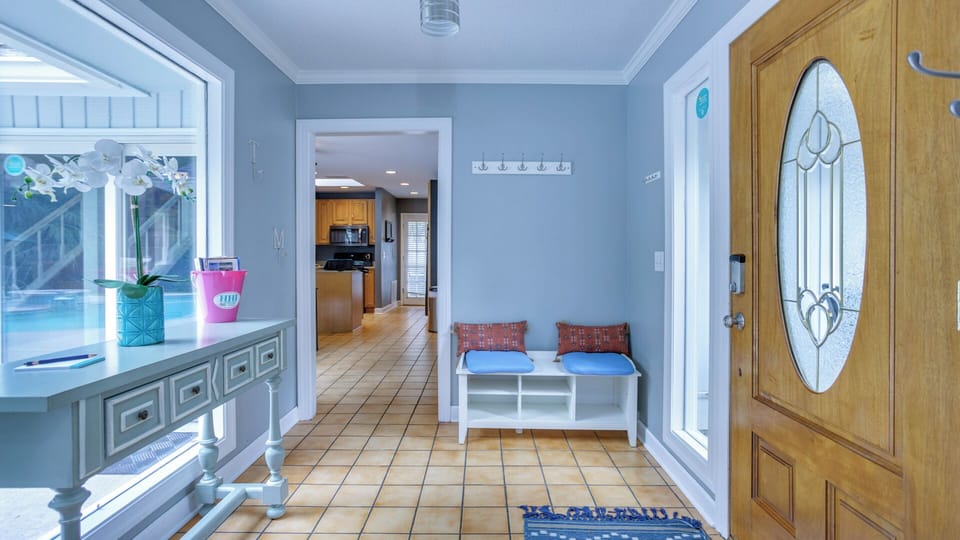 Natural light pours through the oversized window overlooking the pool area, creating a warm first impression for arriving guests.