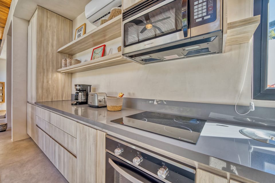 Fully equipped modern style kitchen with induction stove, oven and microwave.